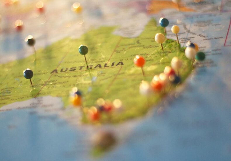 Close-up of a map of Australia with colorful pins marking various cities and destinations.